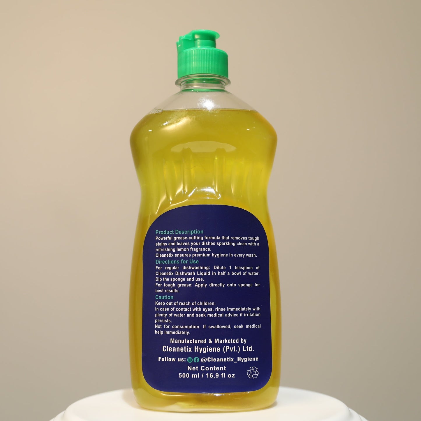 Bottle of dish soap with a green cap on a beige background